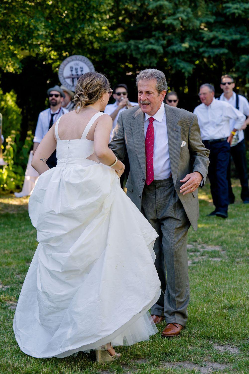 A celebratory dance moment at an outdoor wedding with the band visible in the background.