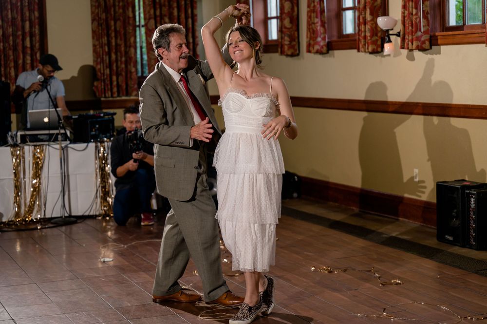 A couple dances together in a rustic venue with wooden floors and walls.