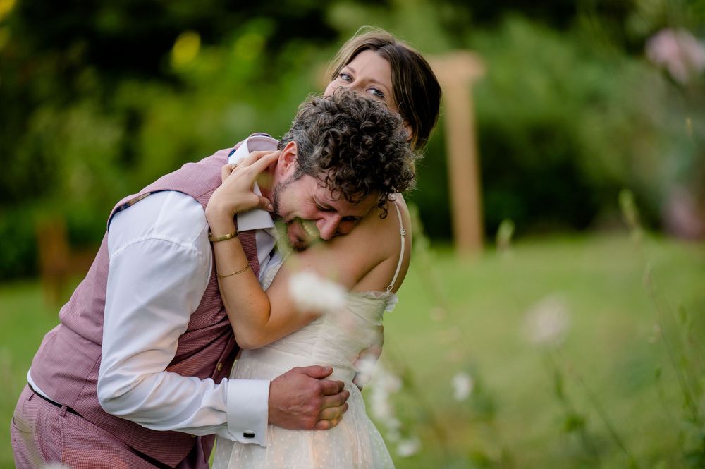 A romantic embrace between newlyweds at an outdoor garden wedding.