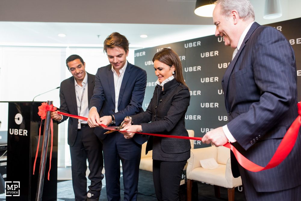 Corporate executives participate in ribbon cutting ceremony at Uber branded event.