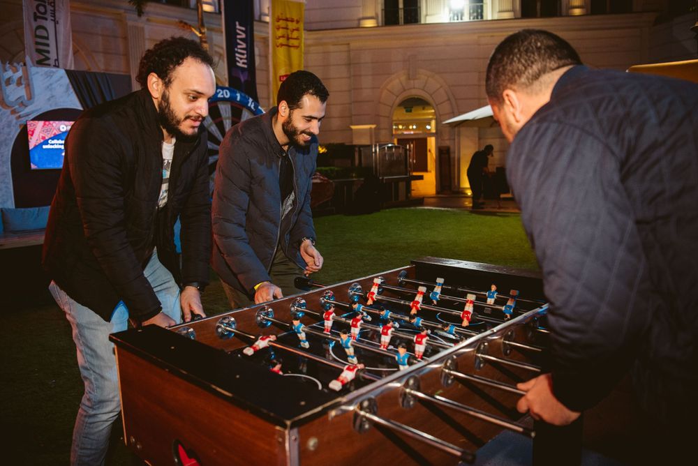 Friends playing foosball table game in evening setting.