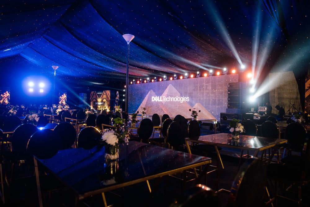 Concert venue with stage lighting and blue tent canopy during an evening performance.