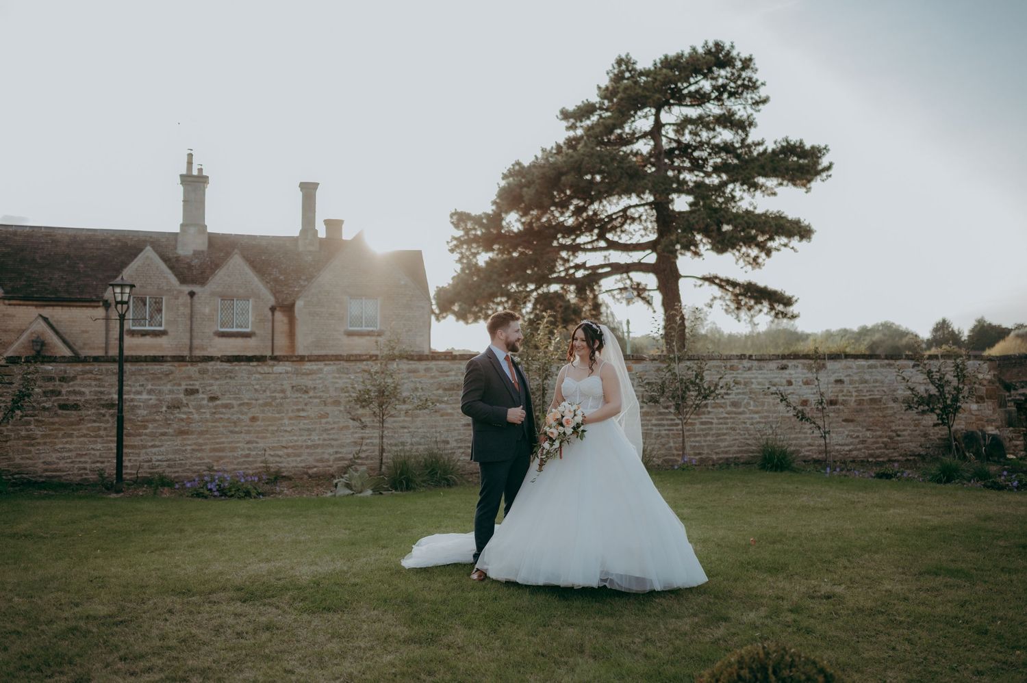 Romantic wedding portrait set against a classic stone wall and grand country house backdrop.