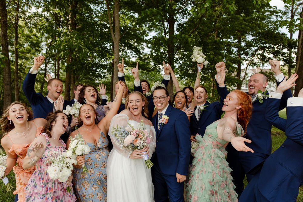 Wedding party celebrating with joyful expressions in an outdoor garden setting.