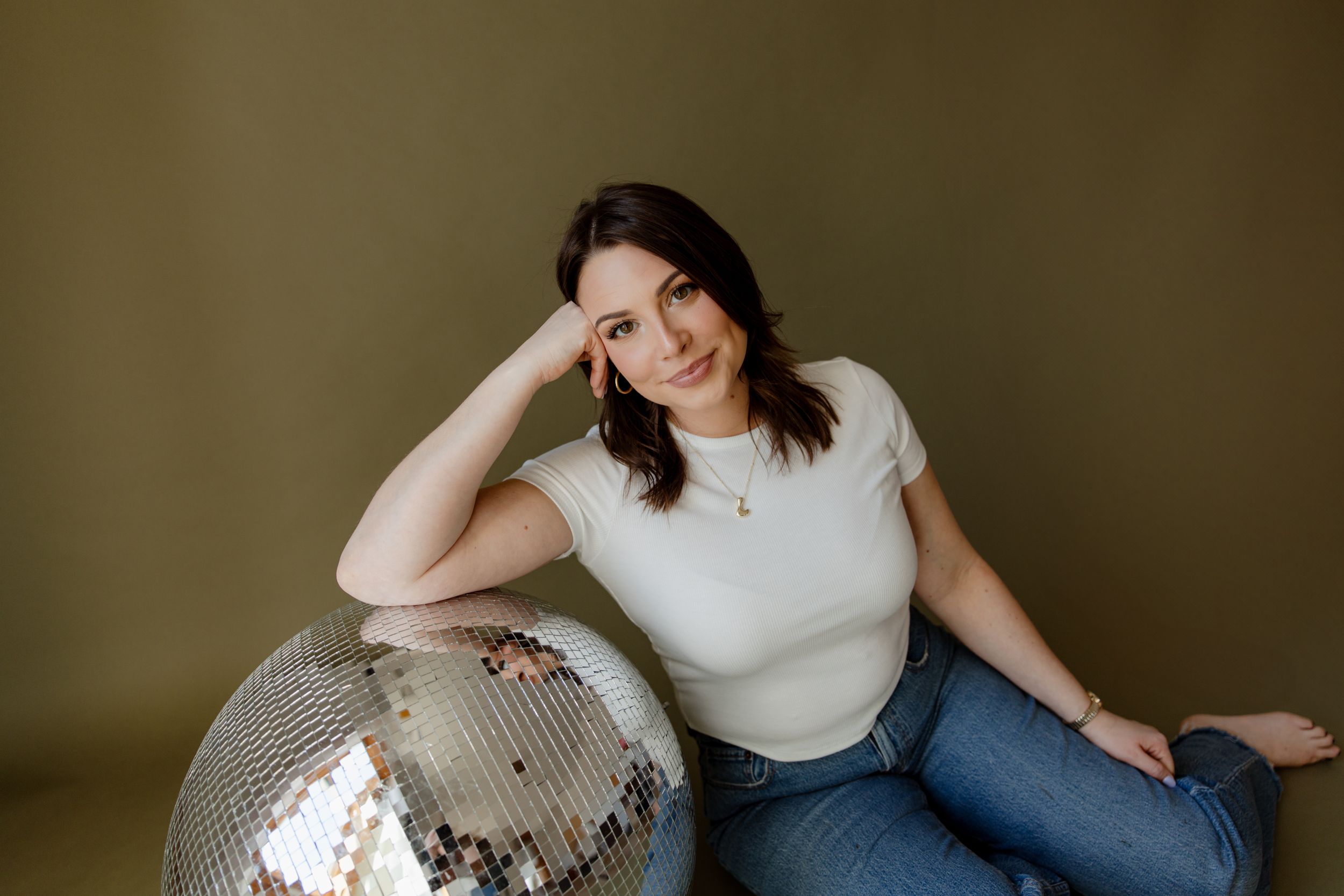 Person in white top relaxing on vintage couch during indoor photo session.