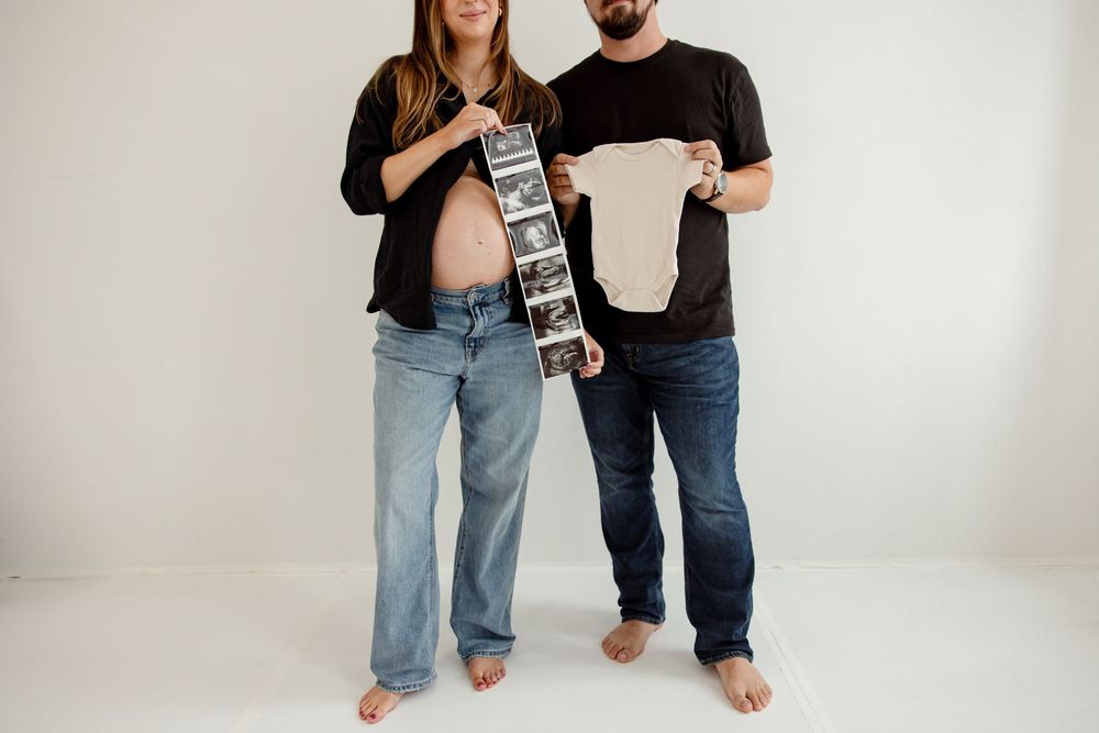 Casual couple posing and having fun with a retro boombox in a minimalist white studio.