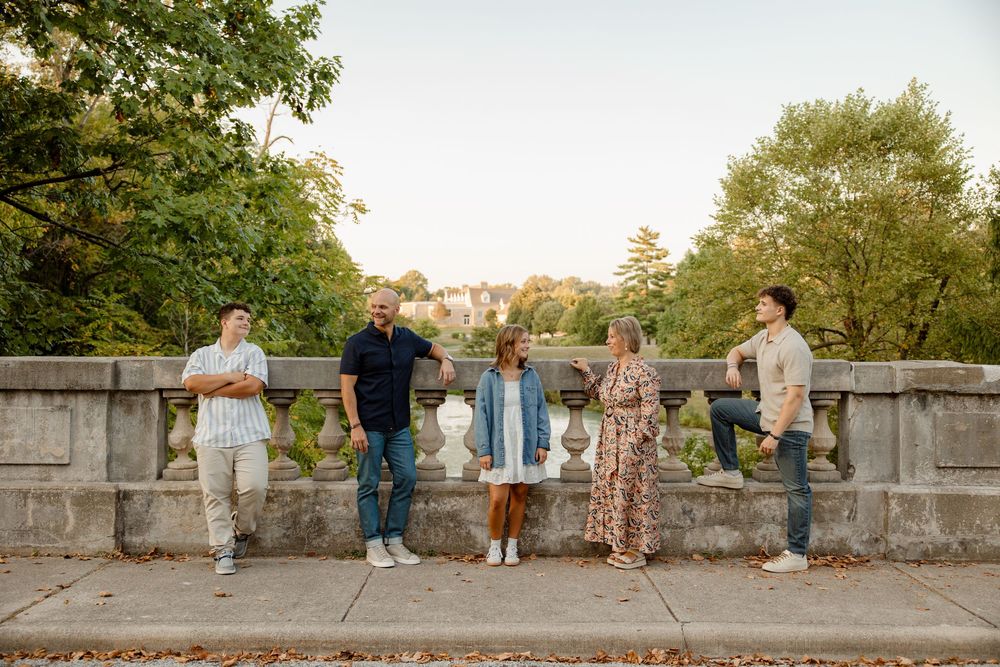 Group photo session of wedding party on stone wall during golden hour.