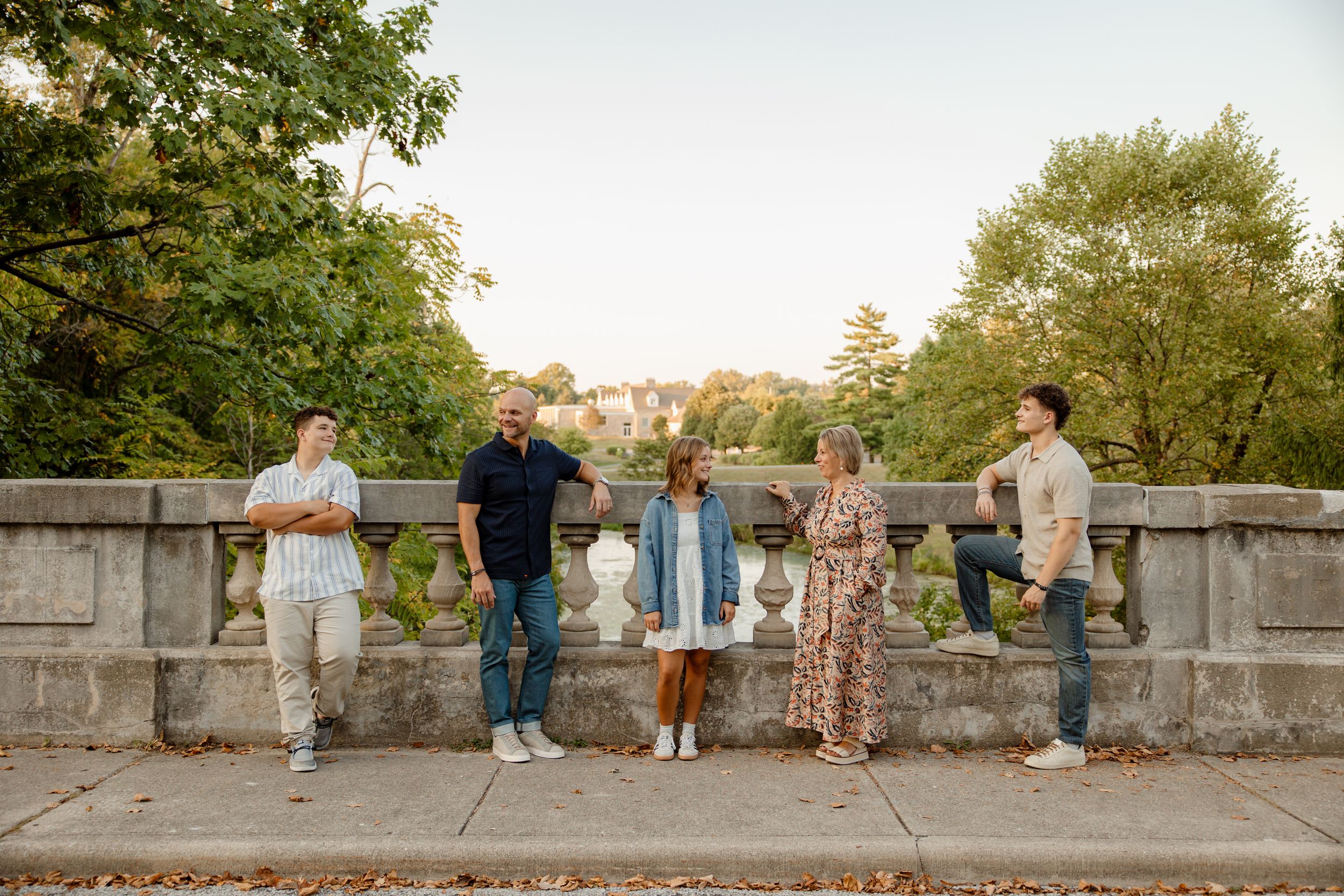 Group photo session of wedding party on stone wall during golden hour.