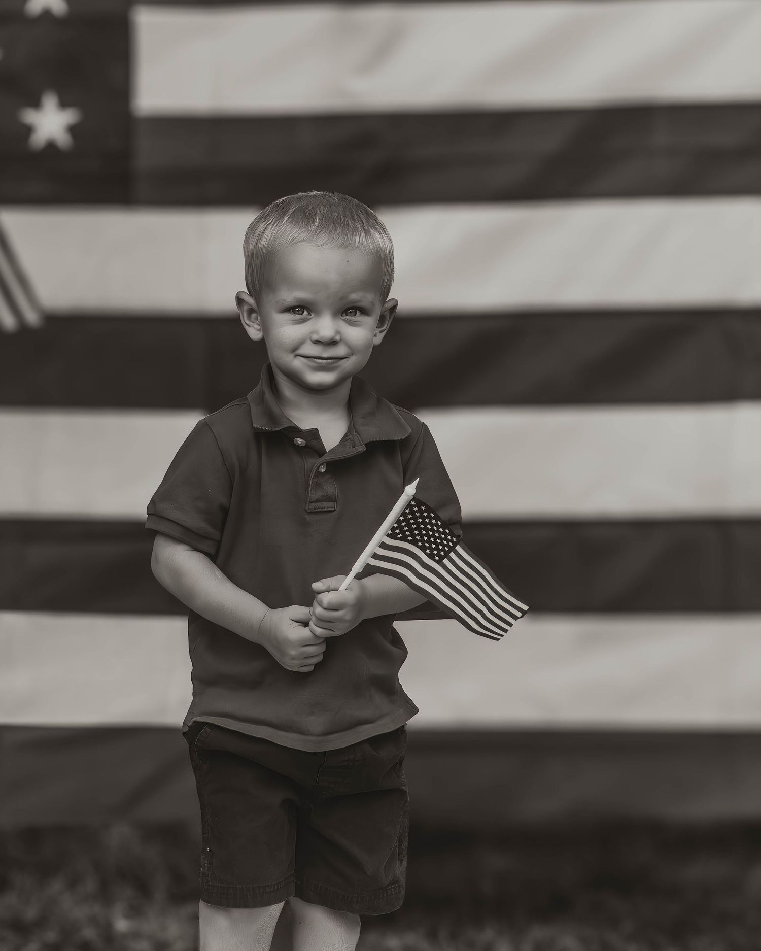 A patriotic scene with a small child holding an American flag against a large striped backdrop.