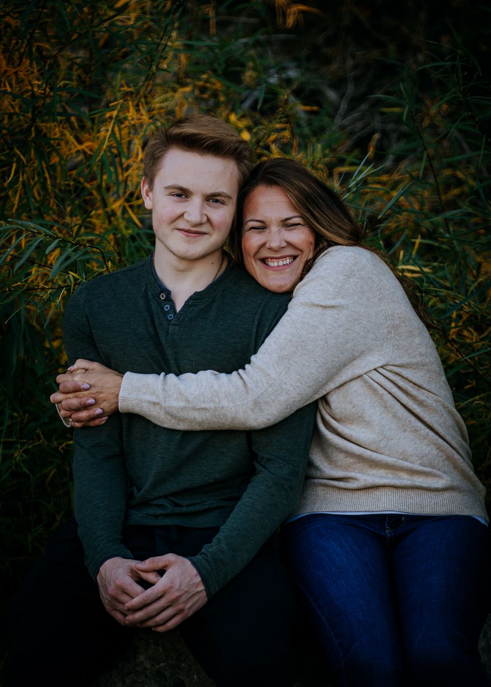 A warm embrace captured in front of autumn foliage during golden hour.