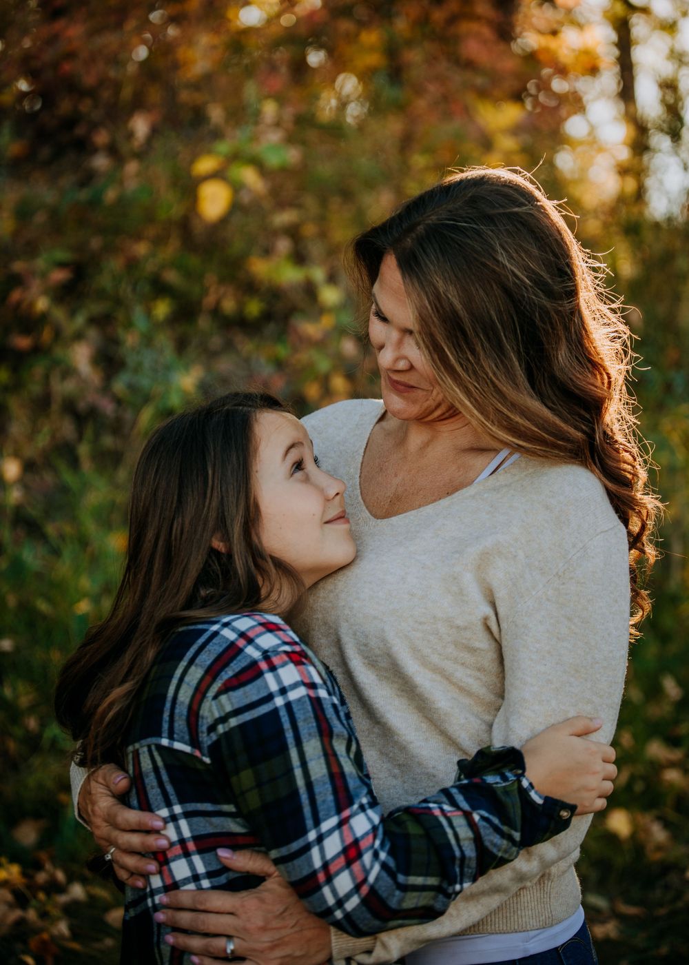 A loving embrace captured during golden hour with autumn leaves in the background.