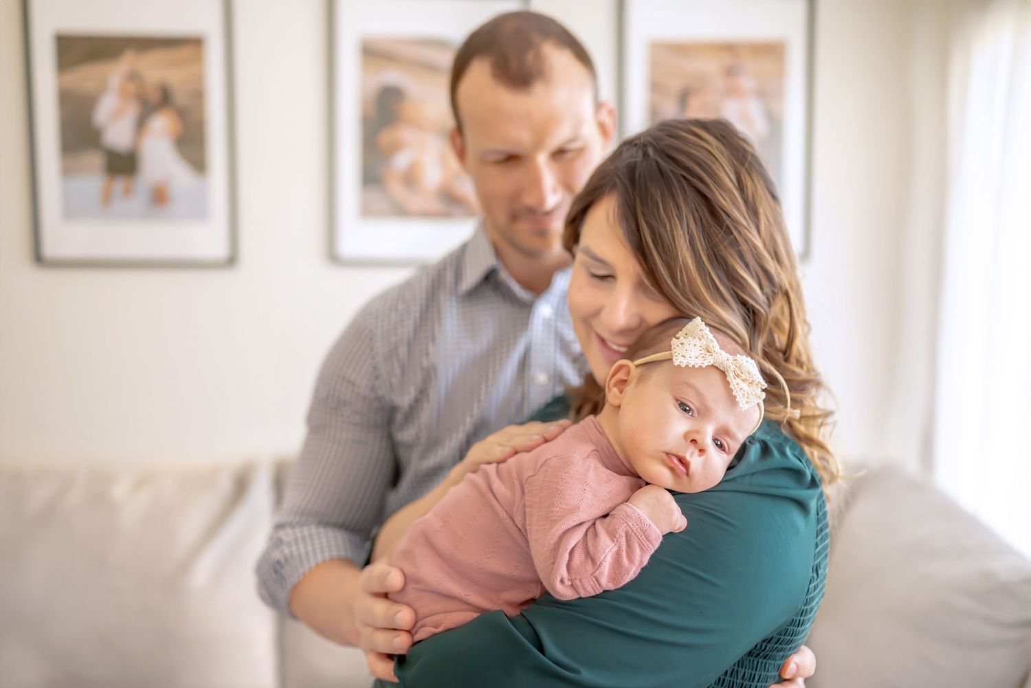 Mom holds newborn daughter, patting her on the back gently. Dad gently embraces mom. Newborn session. Doughman Photography.