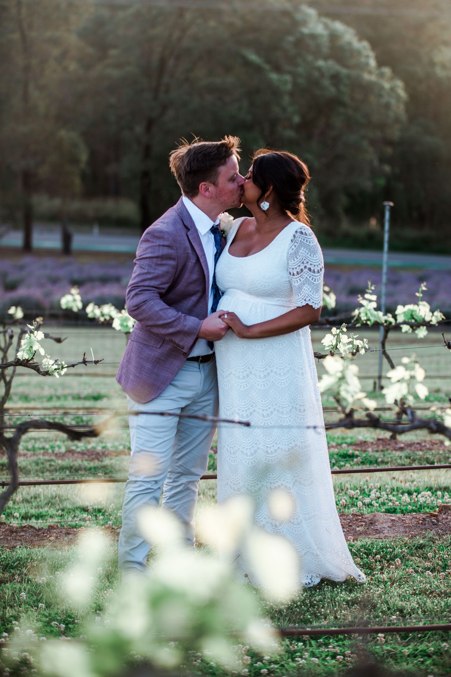 A romantic moment between newlyweds in a garden with lavender and white flowers.