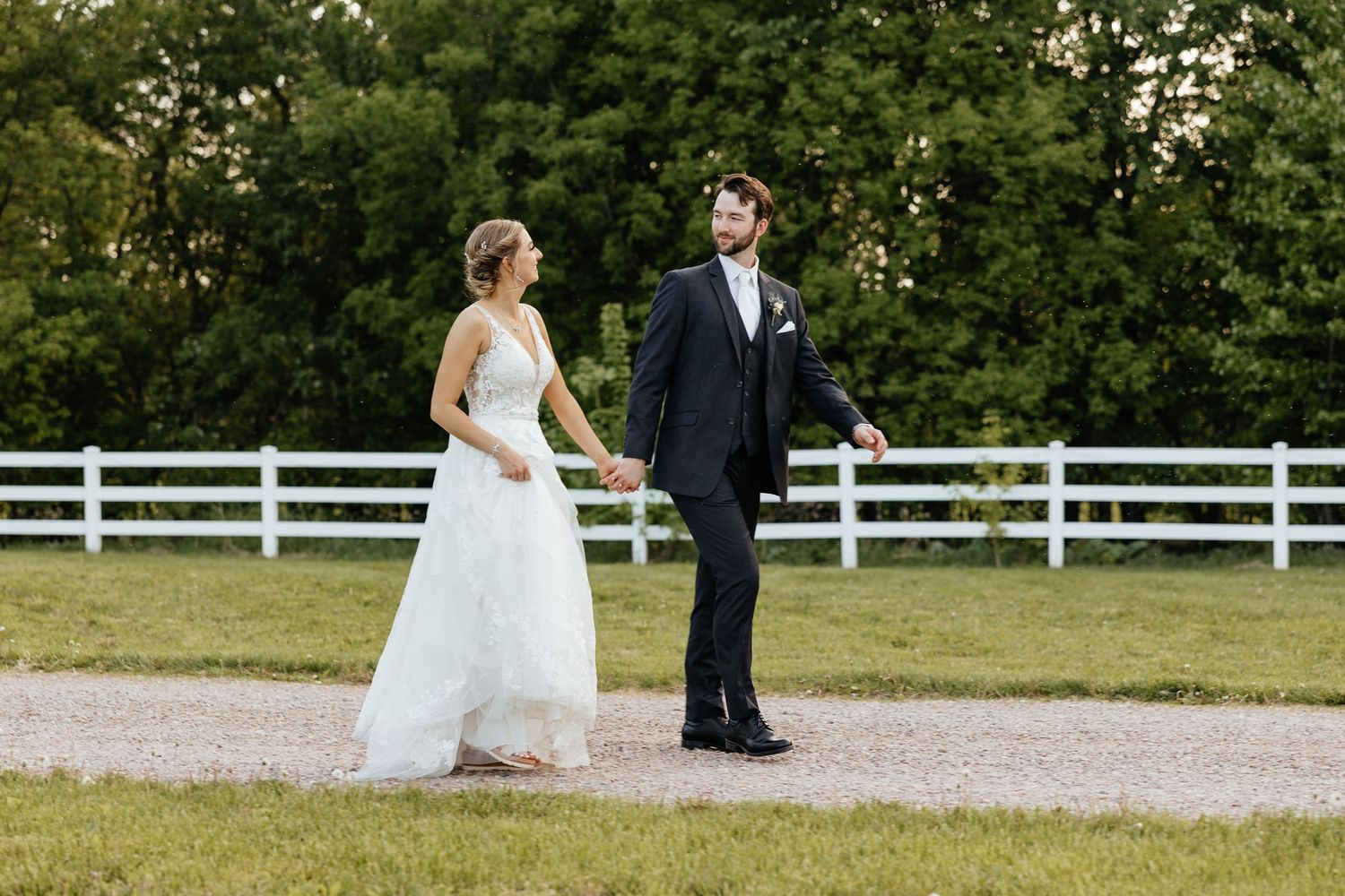 Bride and groom walking on dirt road.