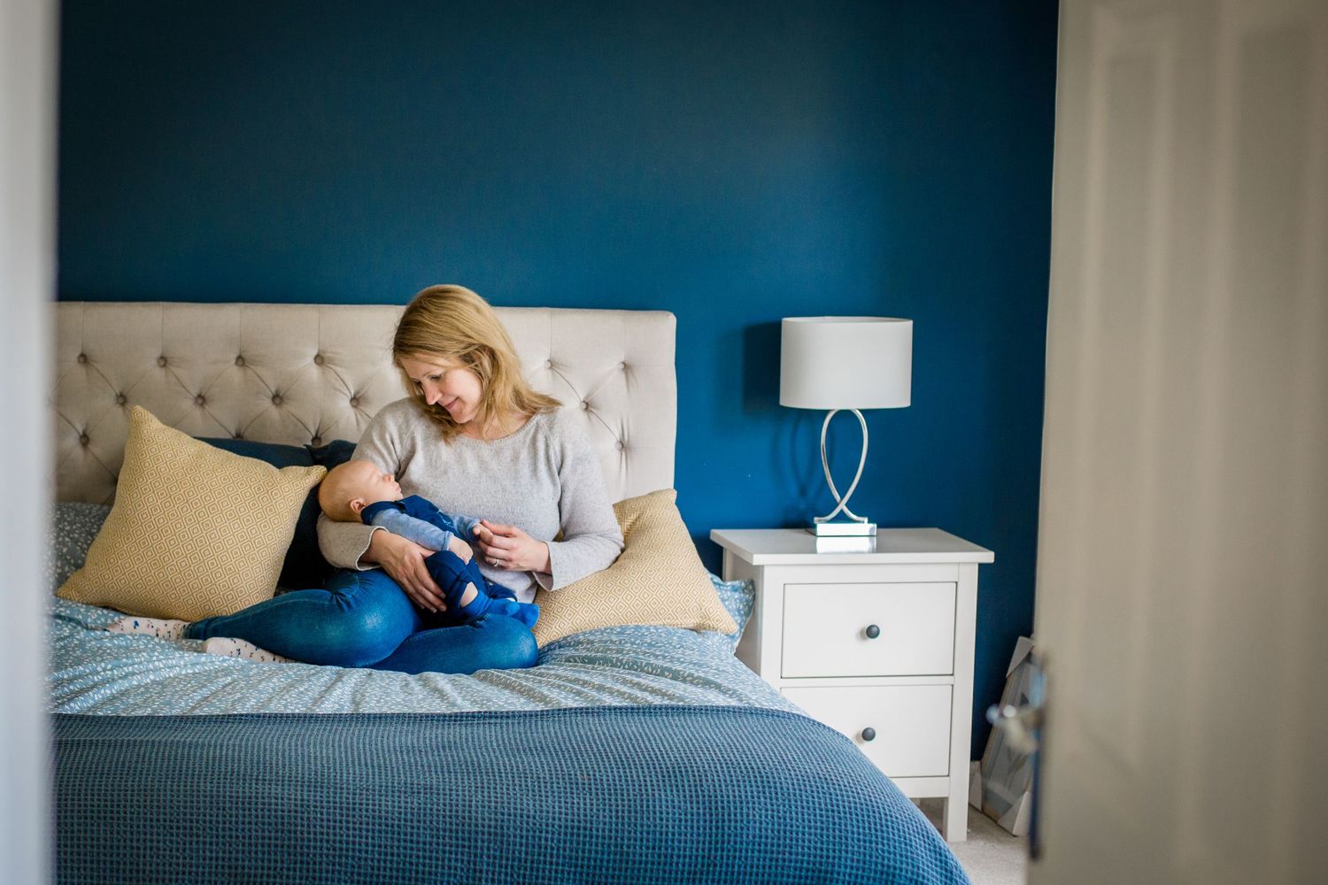 mother and sleeping baby sitting up in bed
