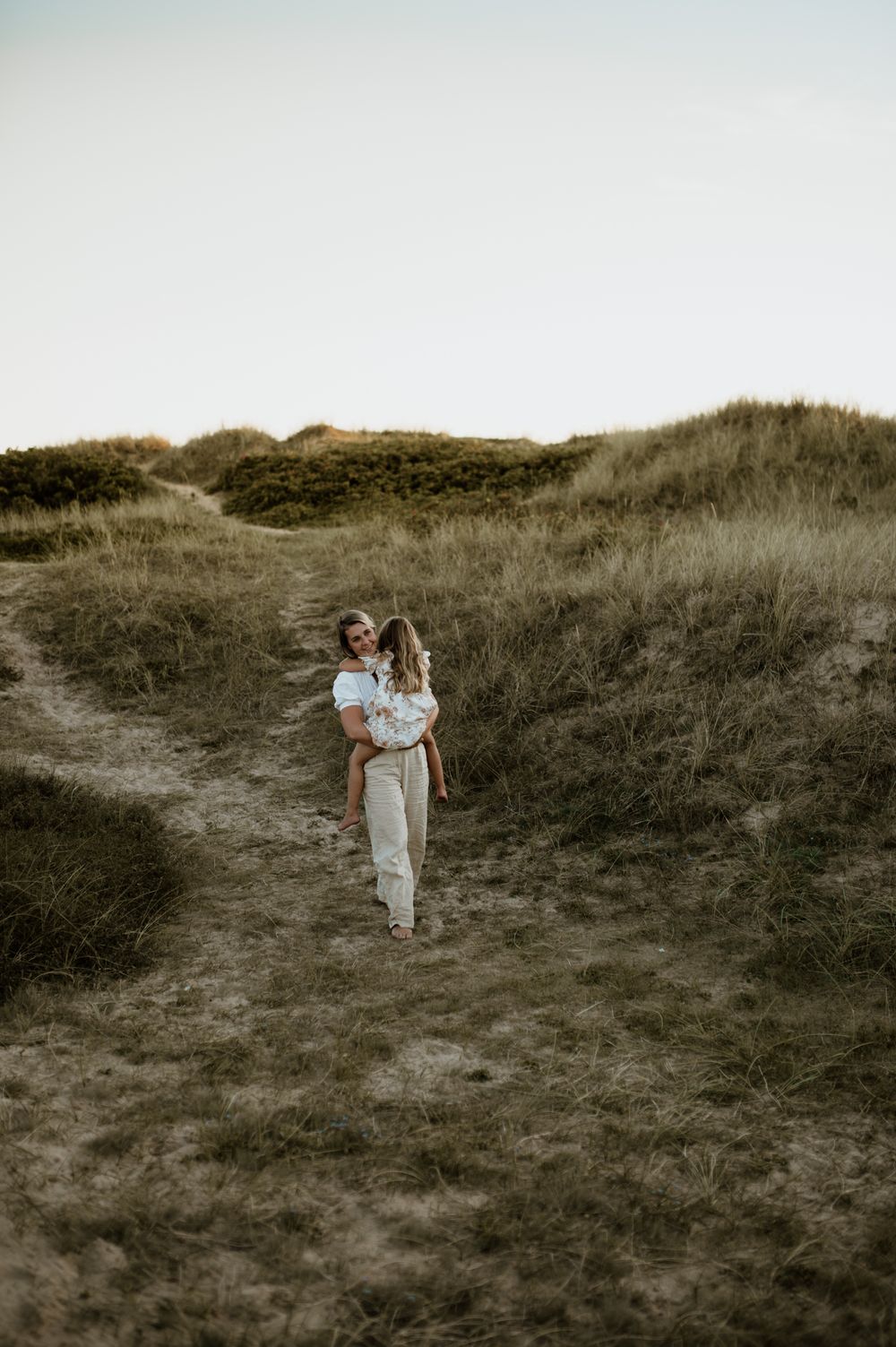 Familj går i sanddynorna på Tylösand.