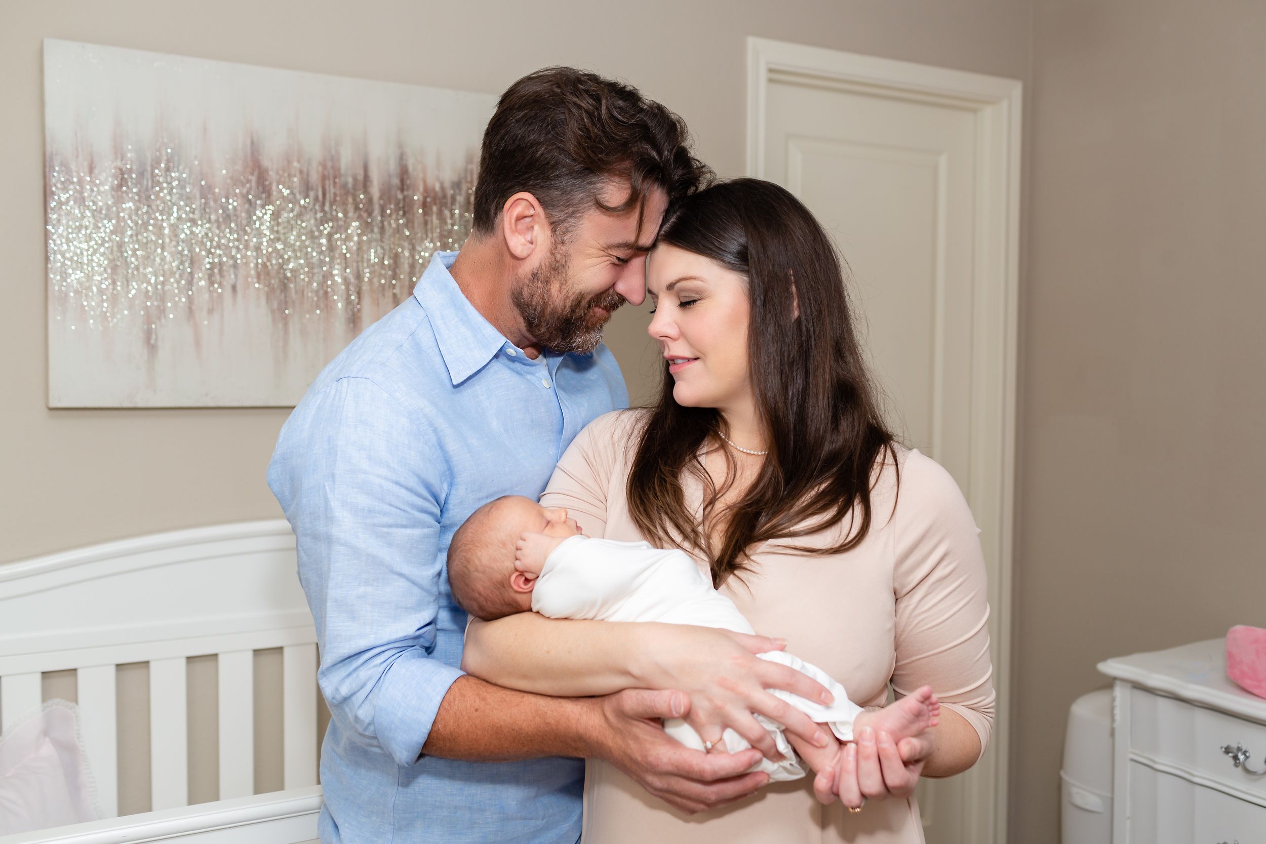 Mom holds newborn baby girl while dad pulls them in close for their newborn session in Houston, TX.