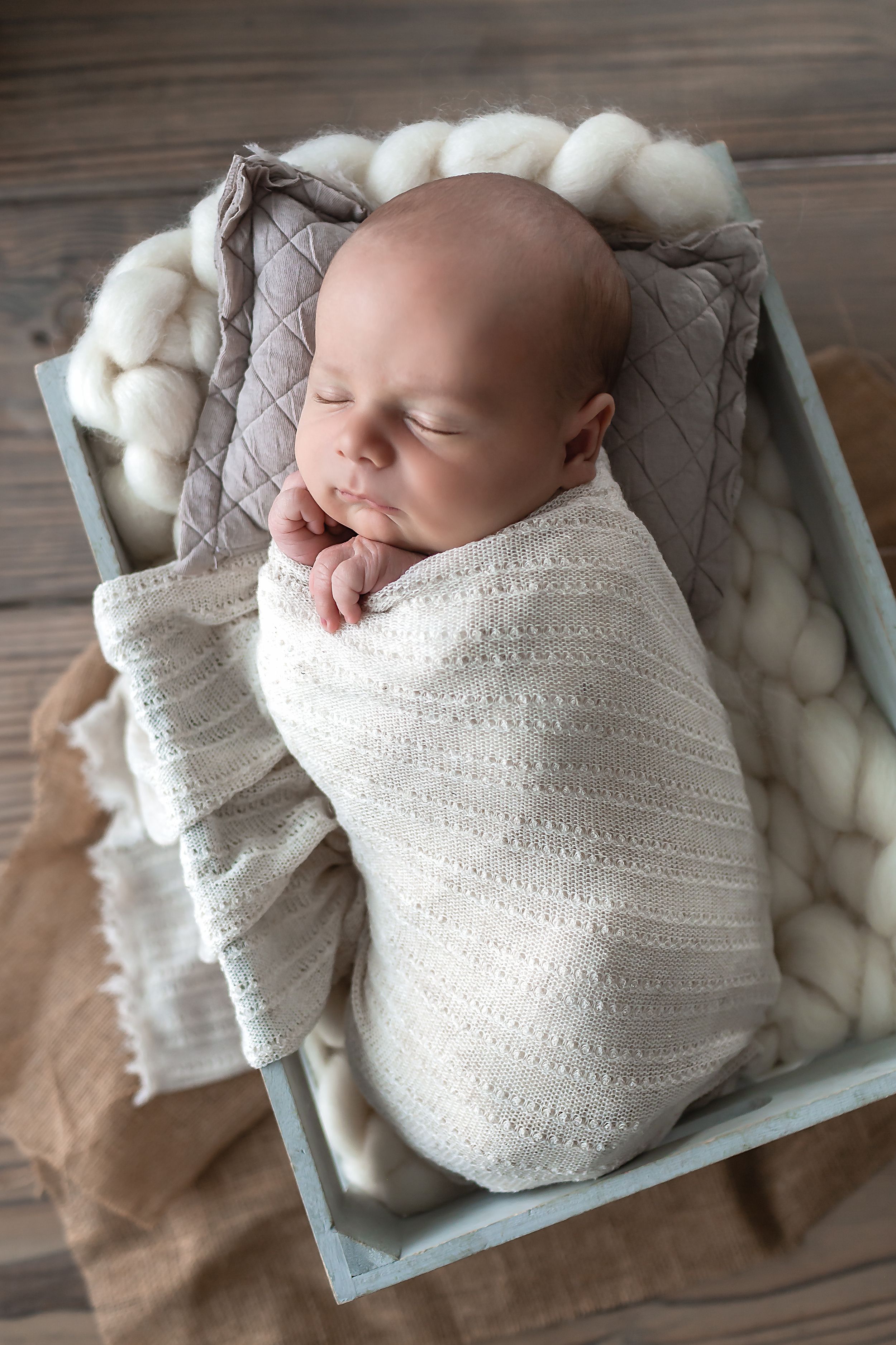 Newborn baby boy posing and sleeping in a crate for his lifestyle newborn session.