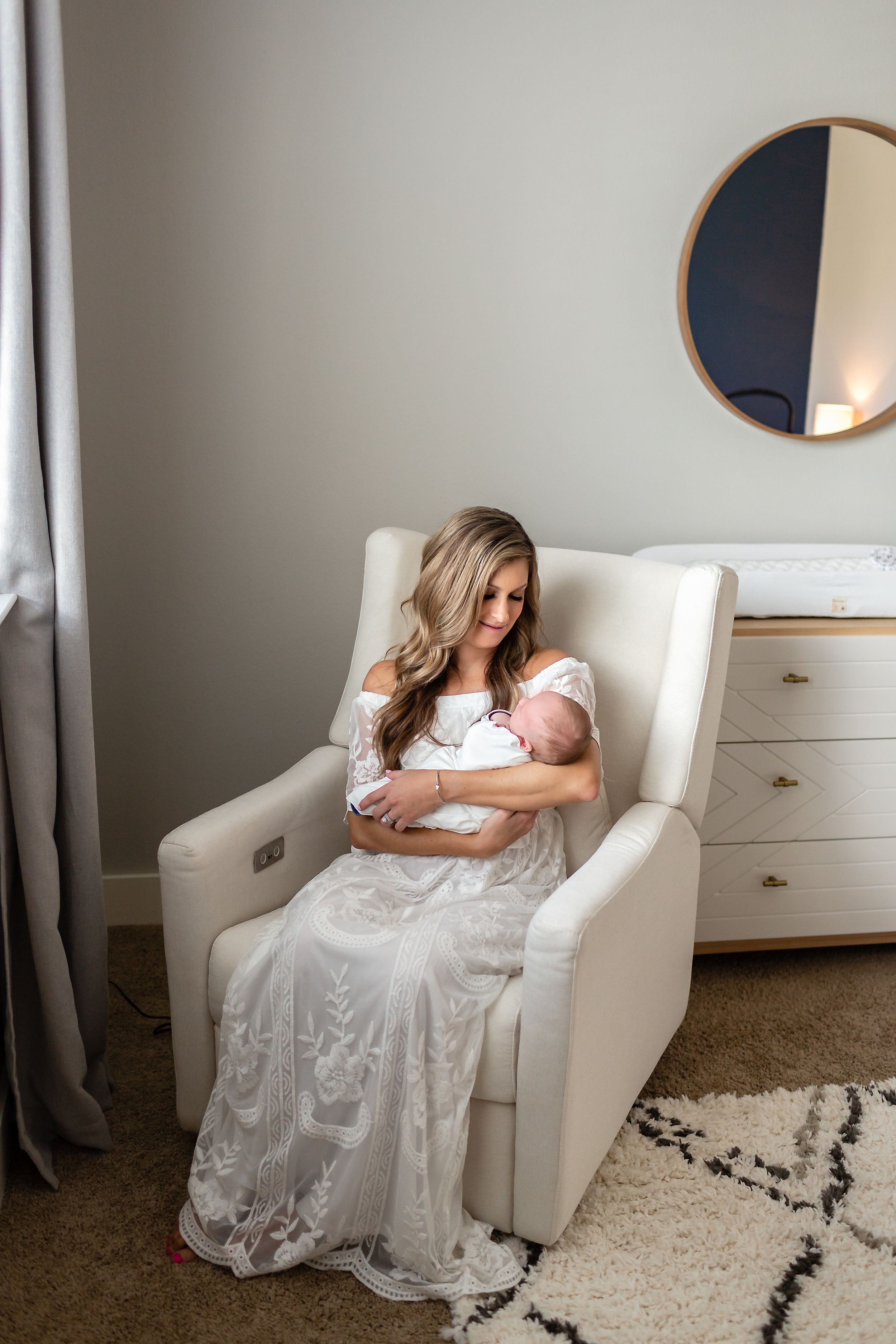 Mom admires her new baby boy in a rocking chair in a nursery in Houston, TX.