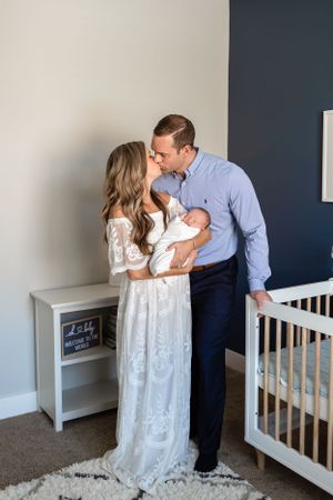 Husband and wife share a kiss while holding their new baby boy in Houston, TX.