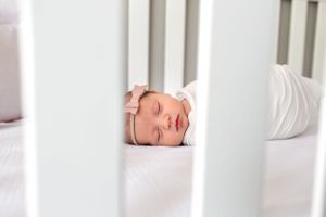 Peeking in at a newborn baby girl asleep in her crib or her newborn session in Houston, TX.