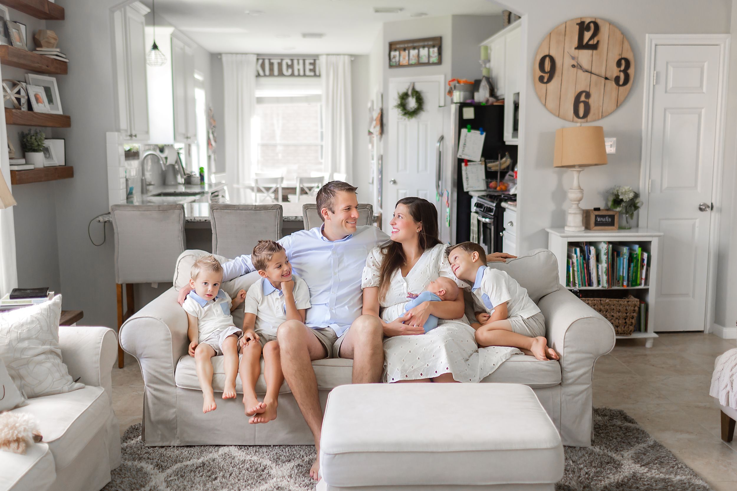 Family of 6 sits on couch snuggling their new baby in Cypress, TX.