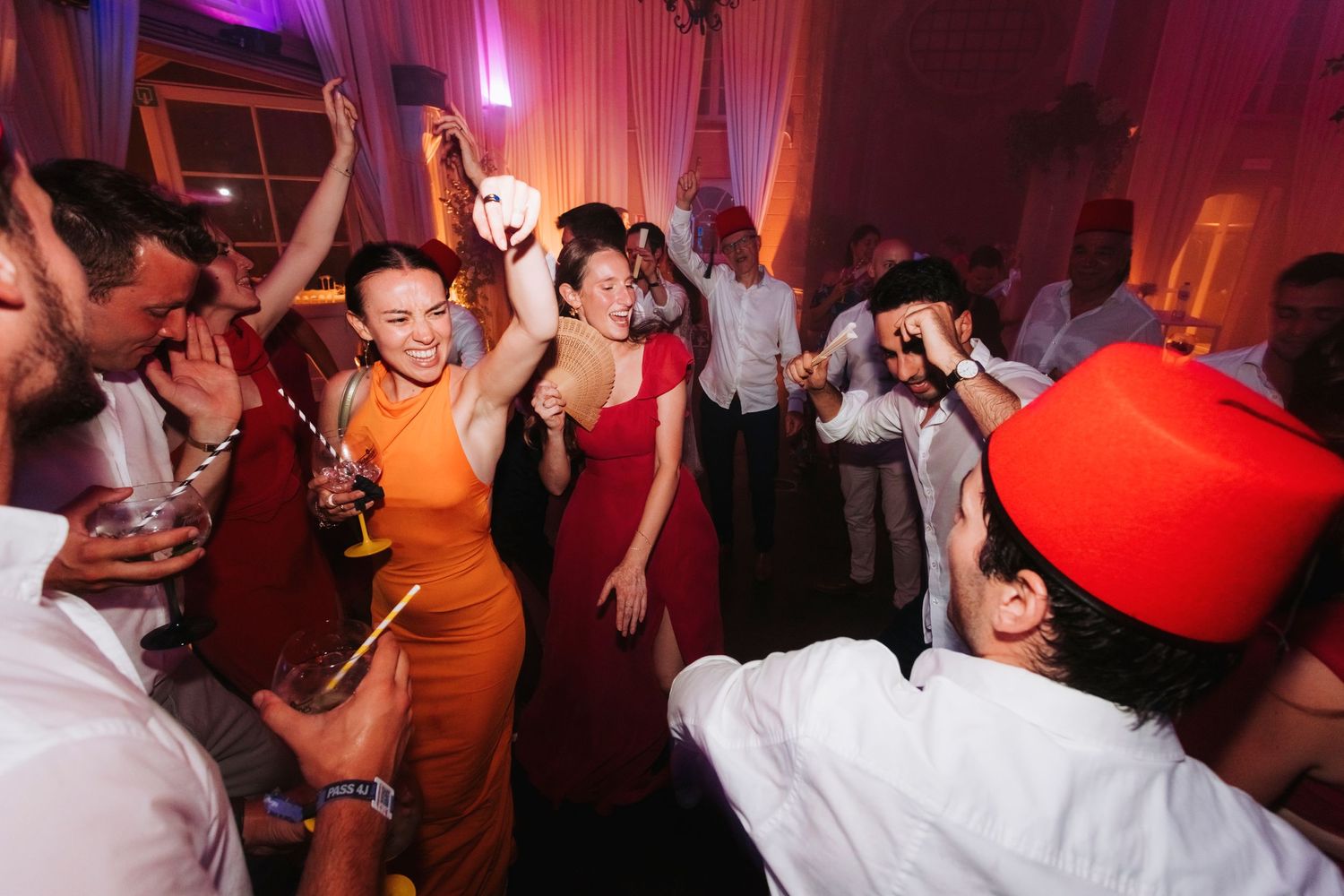 Energetic dance party with guests in vibrant attire under purple mood lighting.