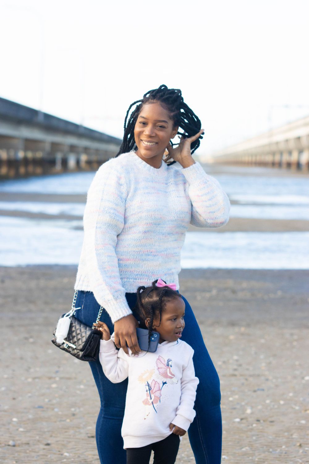 Parent and child pose together at waterfront location.