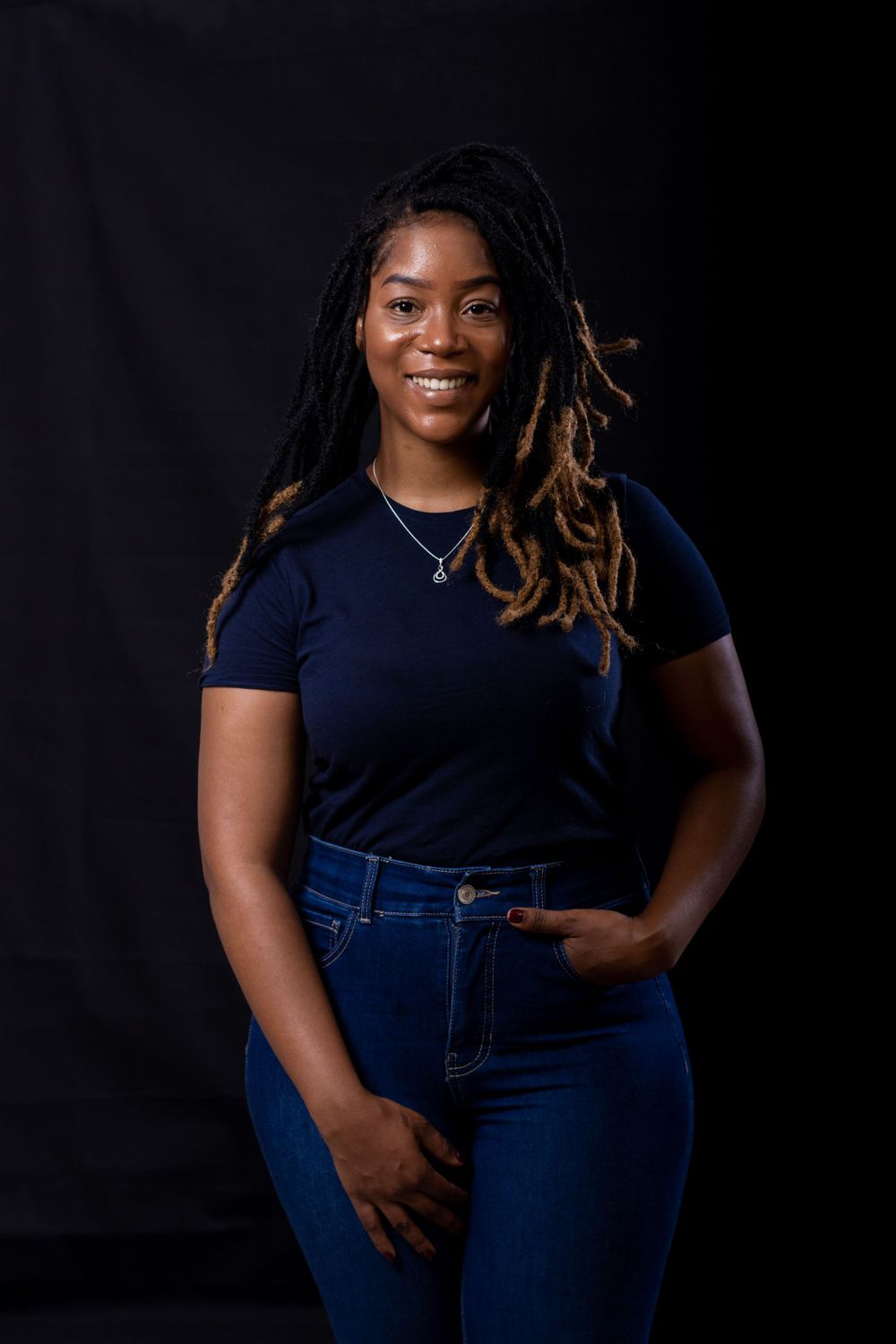 Studio portrait against black background featuring casual navy and denim outfit.