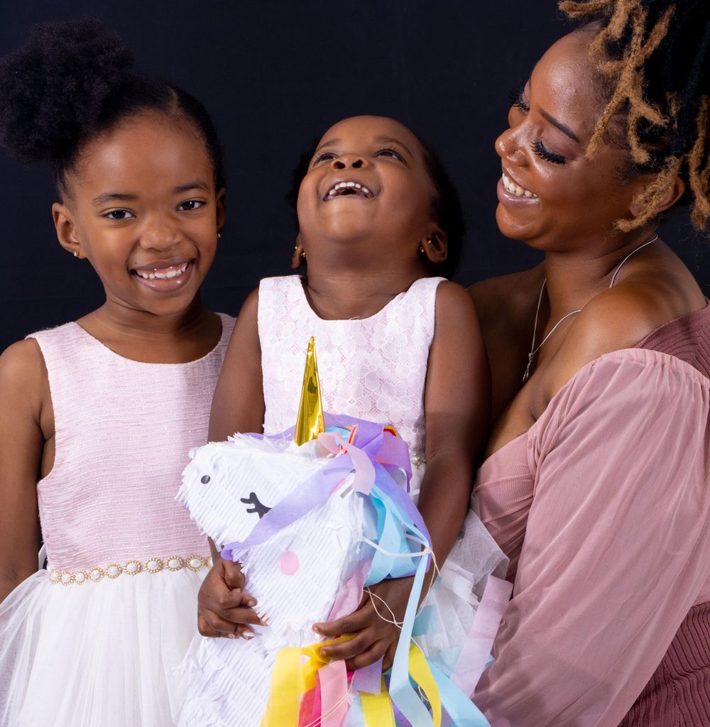 Family moment sharing joy with unicorn party decoration against dark background.