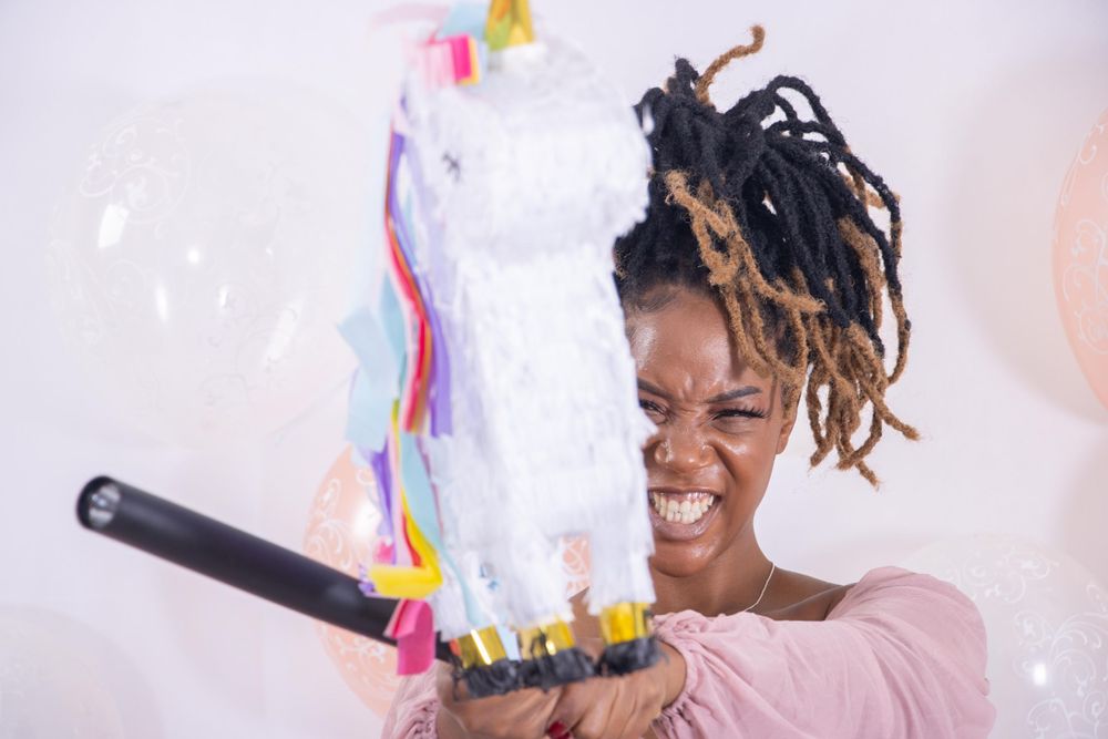 Person laughing while holding a festive party decoration stick with colorful streamers.