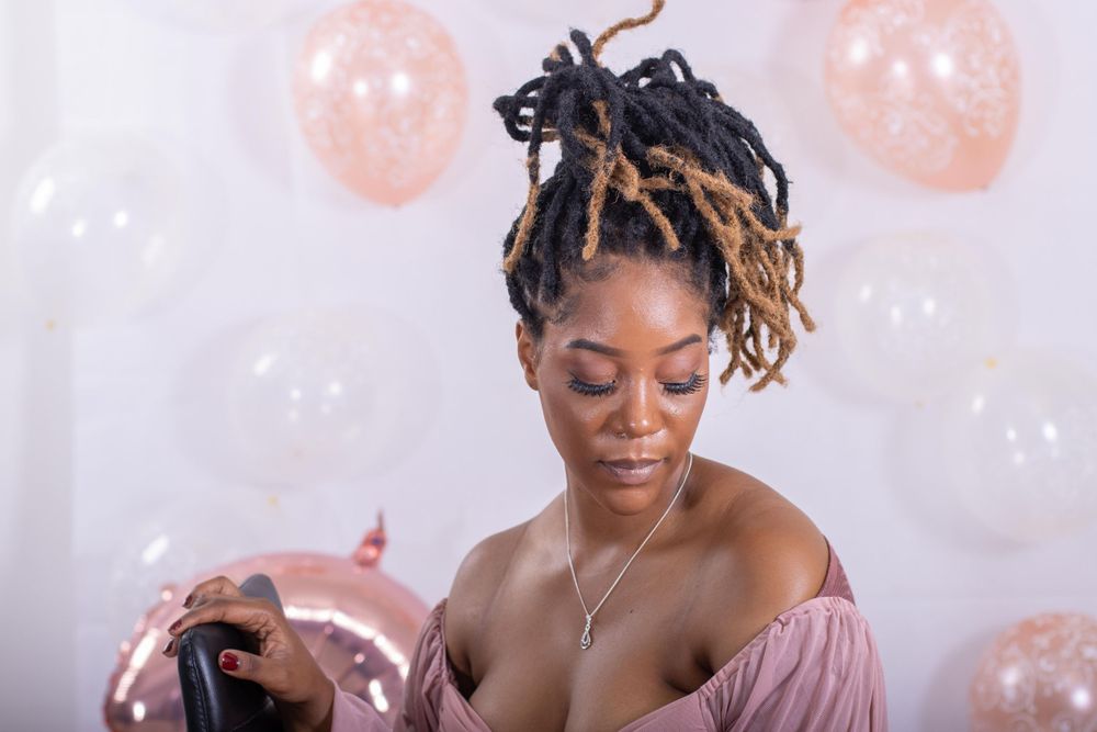 Candid moment at photoshoot with pink balloons in background.