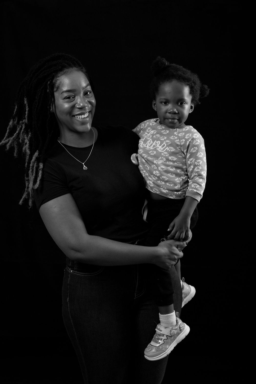 Portrait of parent and toddler in black and white against dark background.