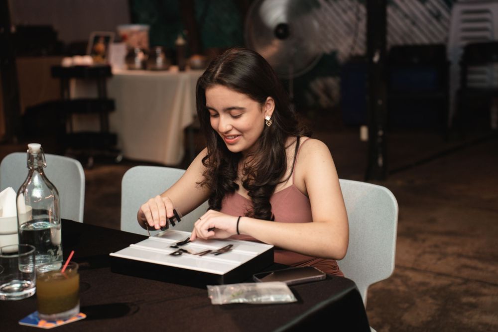 Person writing or signing something at a table with drinks in a dimly lit restaurant setting.