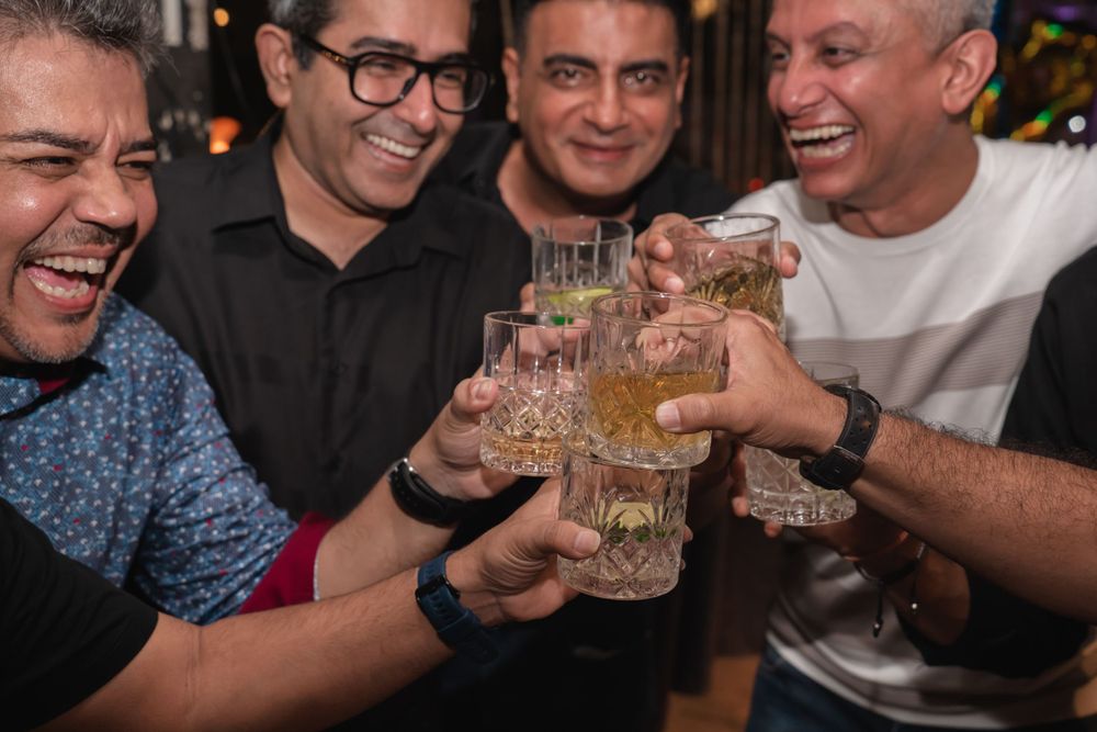 Group of friends toasting with glasses of drinks at a casual indoor gathering.