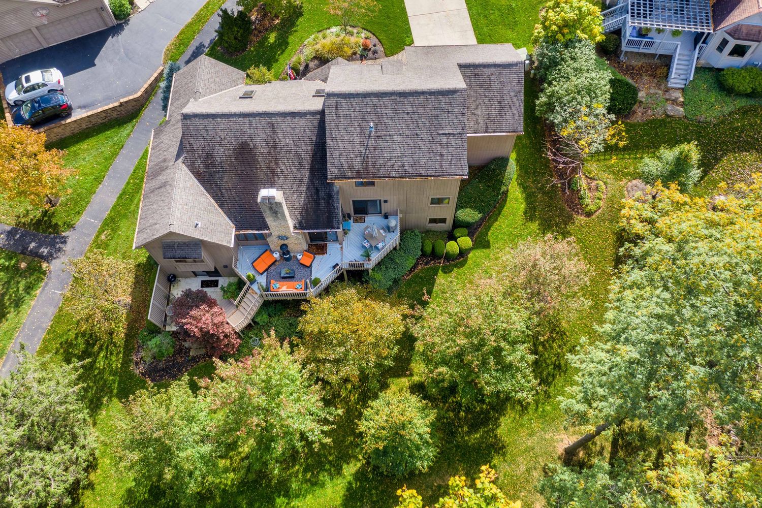 Aerial view of a gray house with deck furniture surrounded by lush green trees and landscaping in Dublin, Ohio.