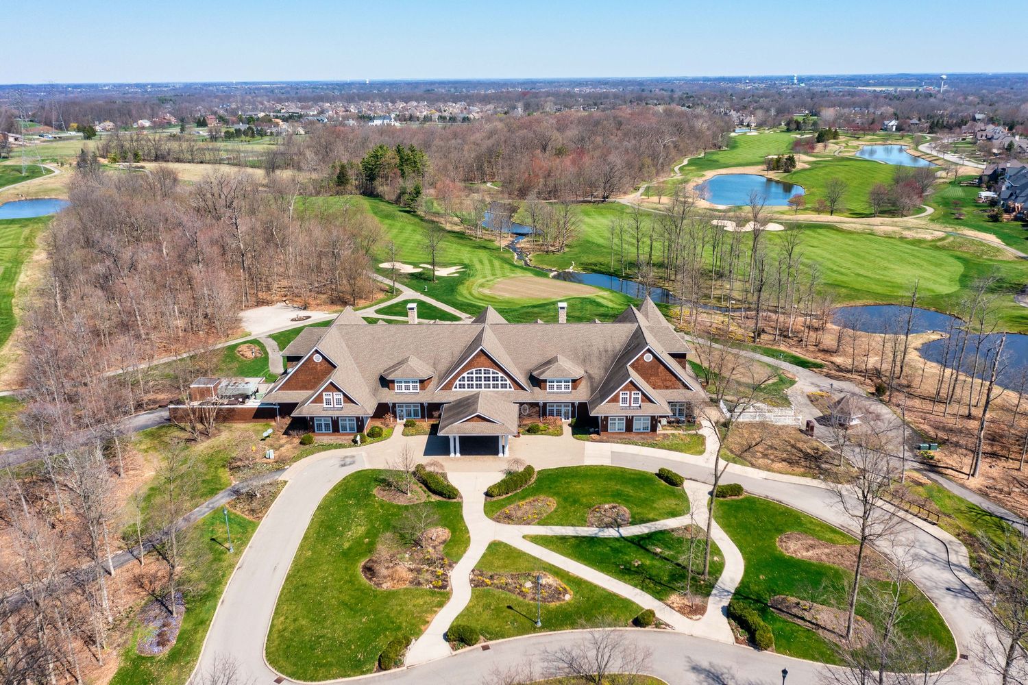 Aerial drone view of a clubhouse with winding pathways and landscaped grounds surrounded by a golf course in Dublin, Ohio.