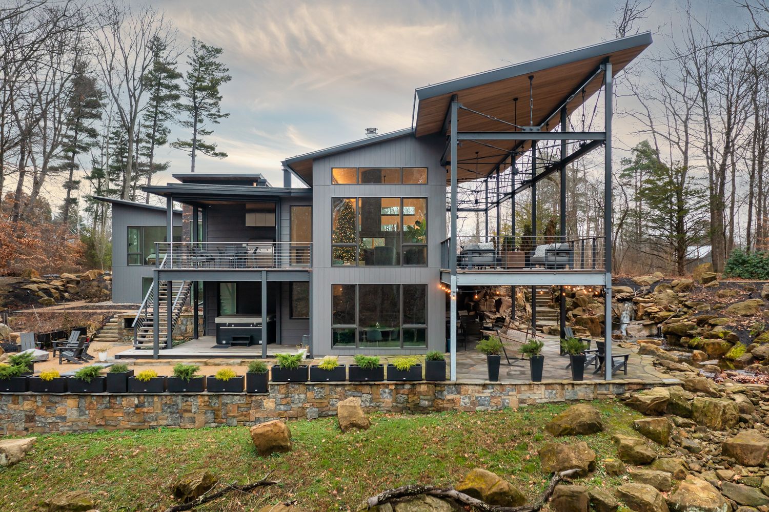 Modern luxury house with angled roofline and glass walls built into rocky hillside showcasing contemporary architecture.