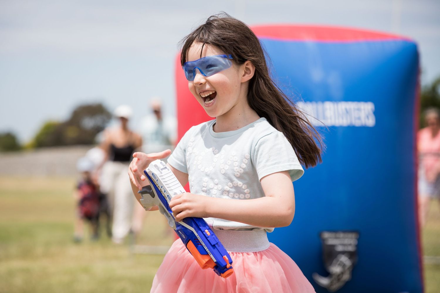 Child at outdoor event wearing face paint and holding blue water bottle.