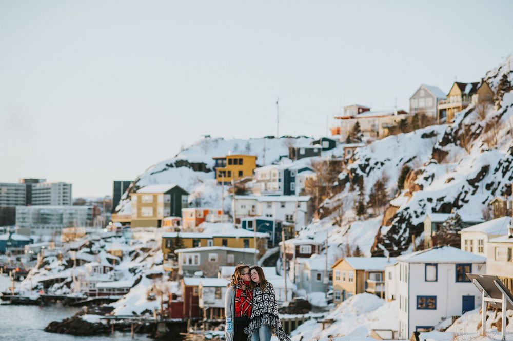 St. John's Lower Battery Houses dot the background, two women cuddle in the foreground.