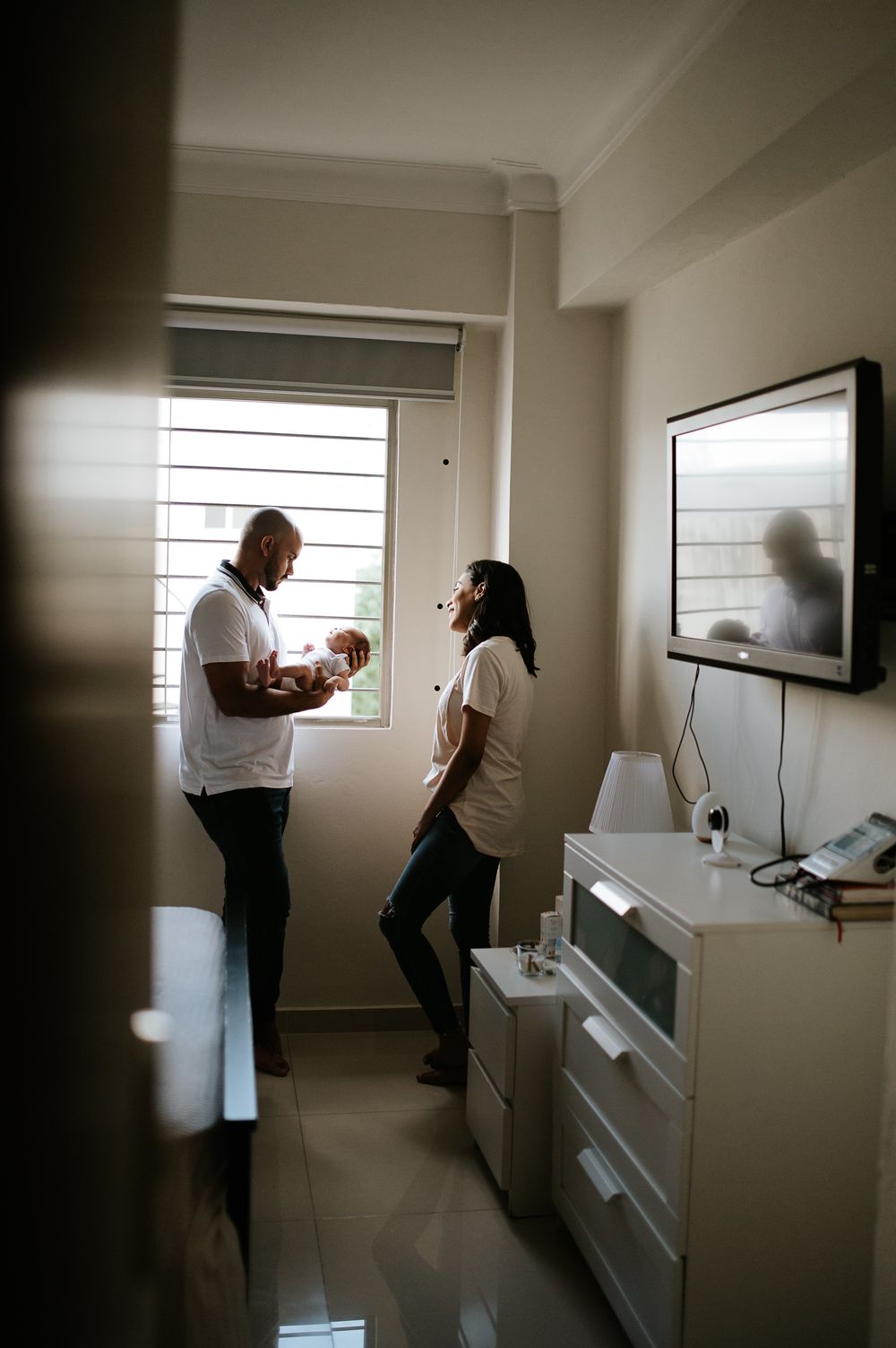 Couple standing in a bright room with window light and modern furniture.