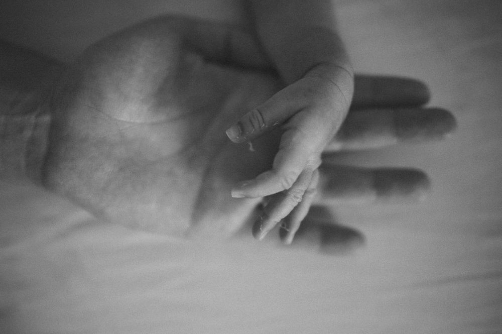 Artistic black and white macro shot of small baby hand against soft background.