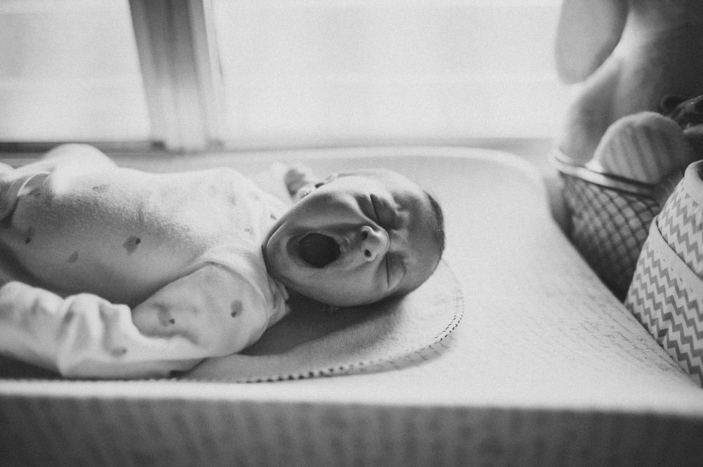 Black and white close-up of a baby lying on a changing mat.