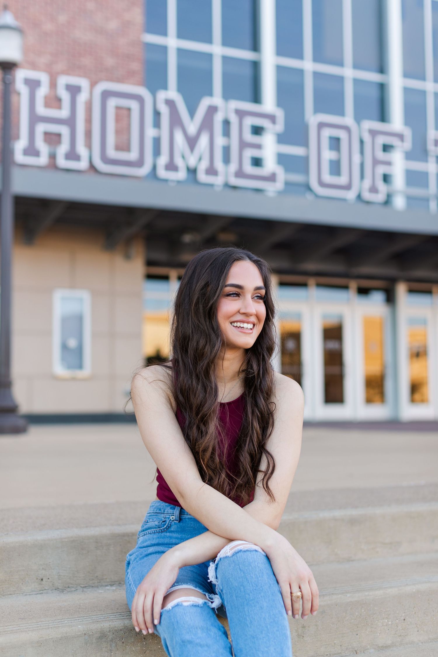 A casual portrait outside a building with 'HOME OF' text visible in the background.