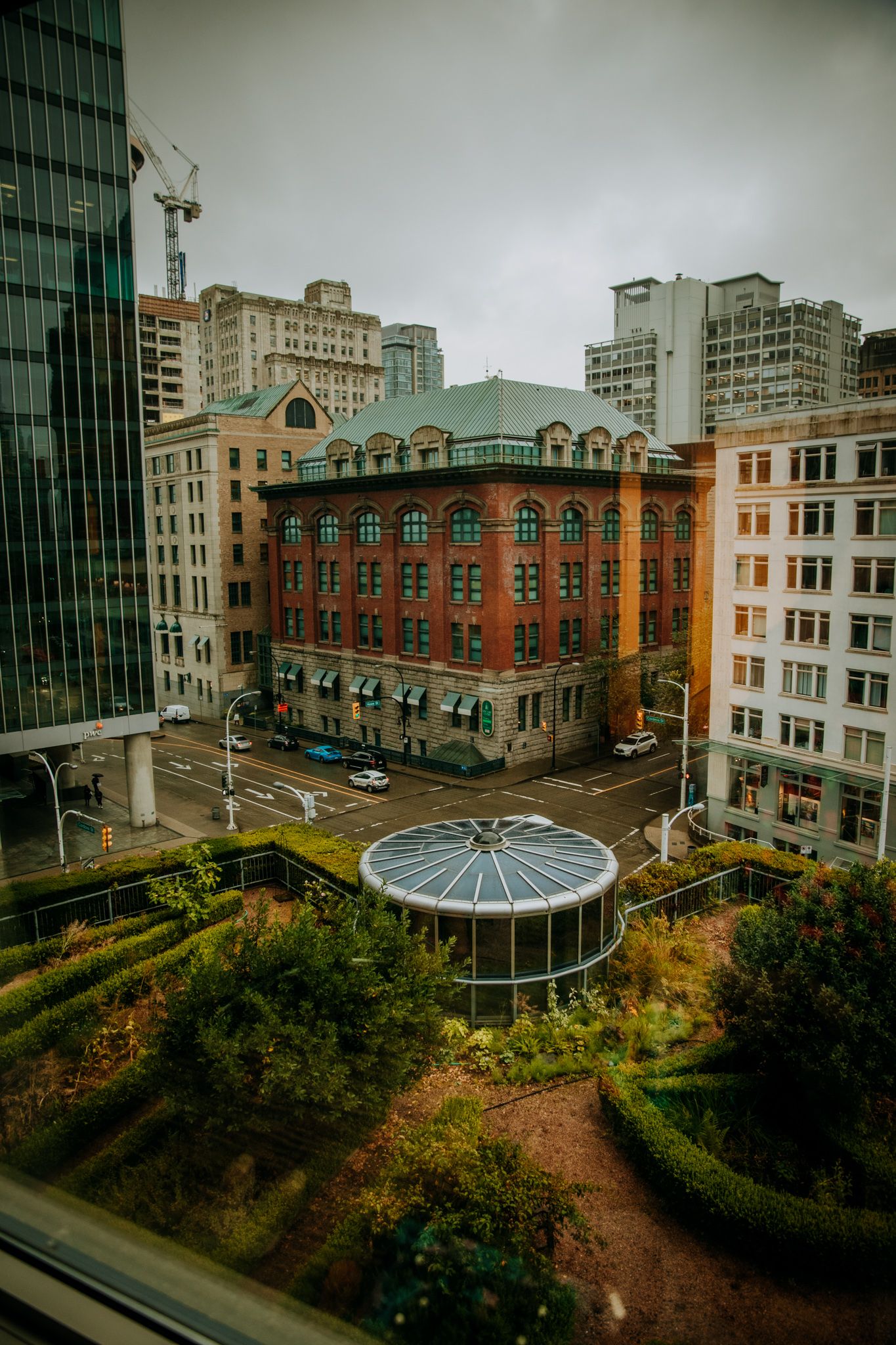 Urban cityscape featuring historic red brick buildings and a glass dome garden structure.