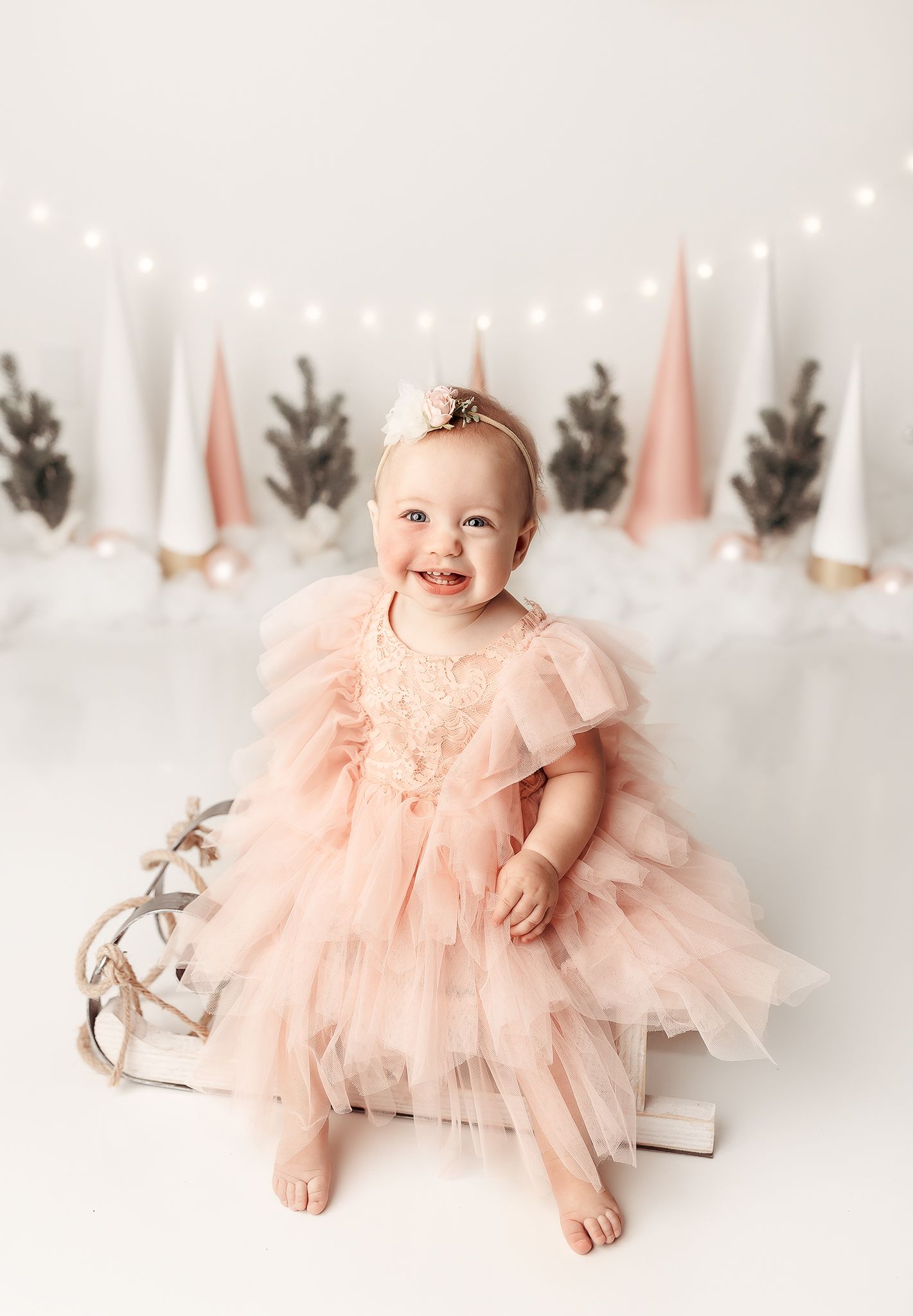 one year old baby sitting on a sled at her winter theme cake smash in Tulsa, OK
