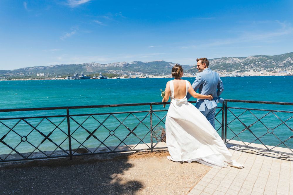 Couple enjoying panoramic sea views from stone balcony overlooking turquoise waters.