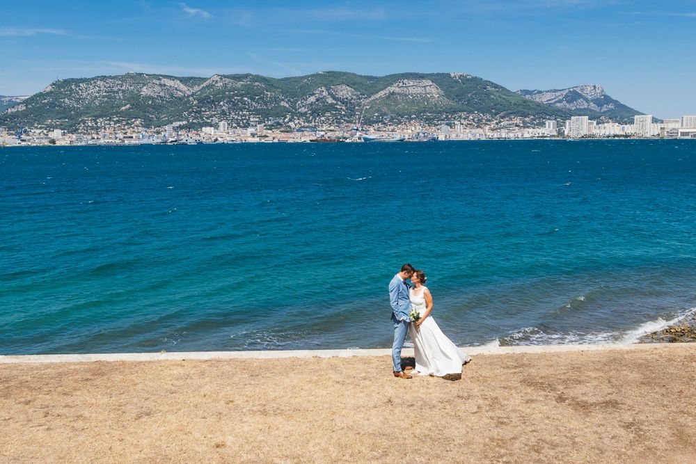 Scenic beach scene with crystal blue waters and mountainous coastline in background.