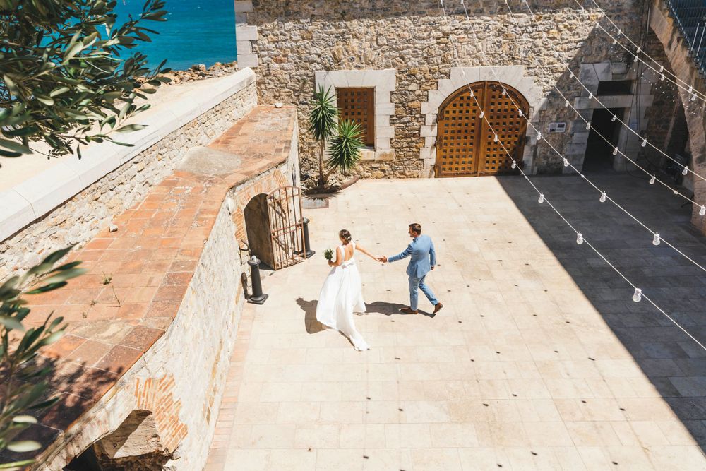 Two people dancing on an outdoor terrace surrounded by Mediterranean stone architecture.