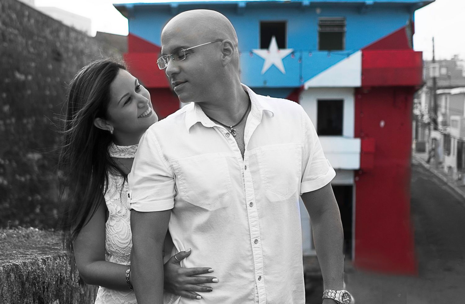 Couple posing in front of house with Puerto Rican flag mural.